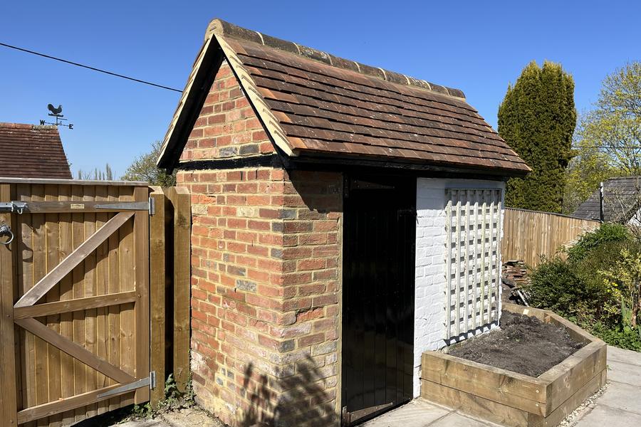 A rebuilt garden outbuilding with a new clay tile roof, brick gable and paving